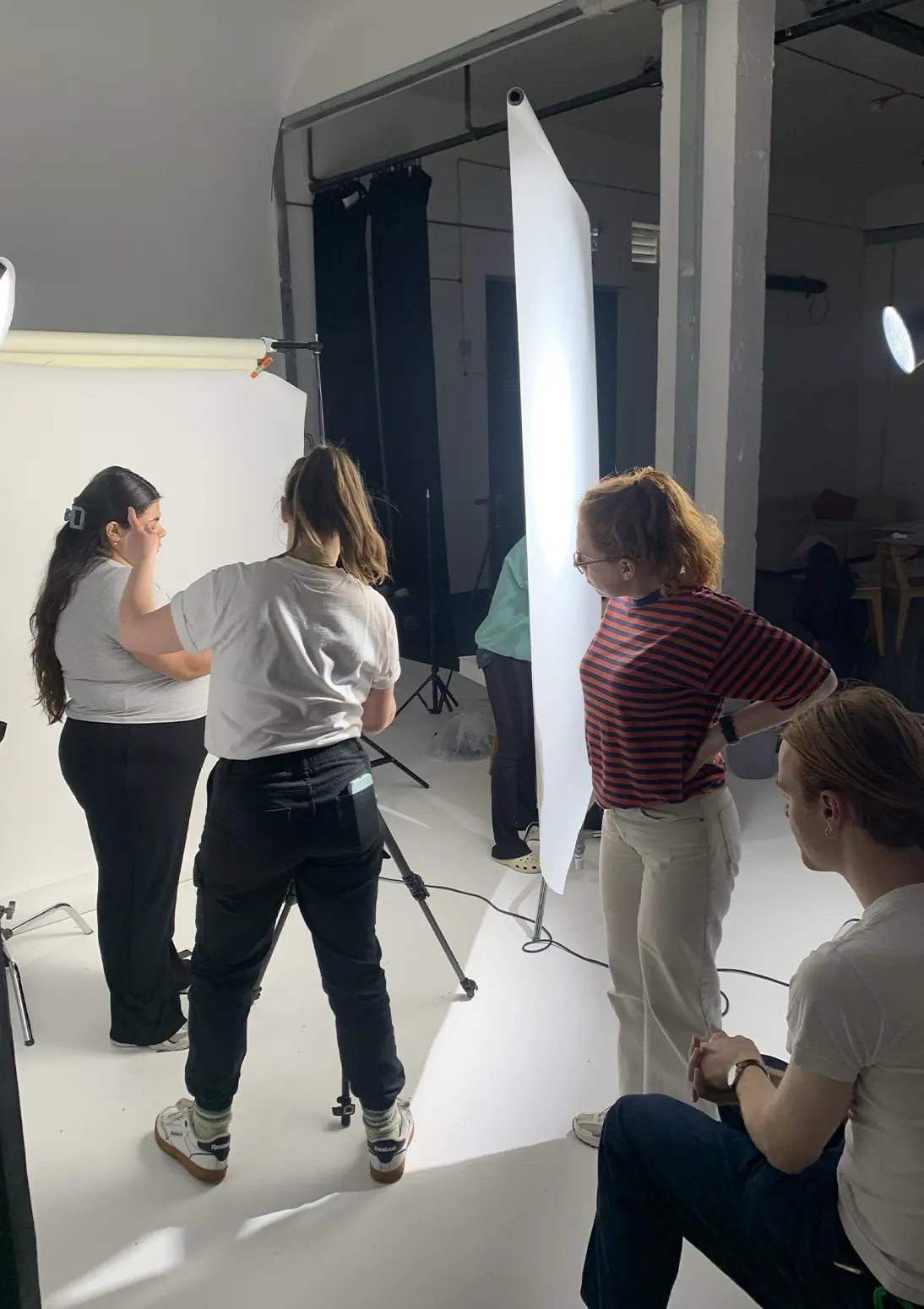 A small crew setting up a studio shoot, with people adjusting lighting and camera equipment around a white backdrop.